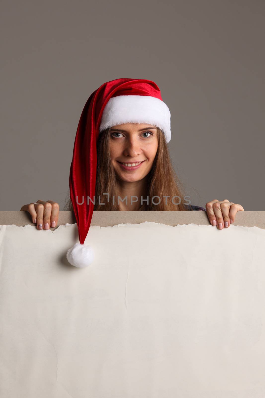 Santa girl holding blank vintage sign billboard. Christmas woman in Santa hat showing paper sign.