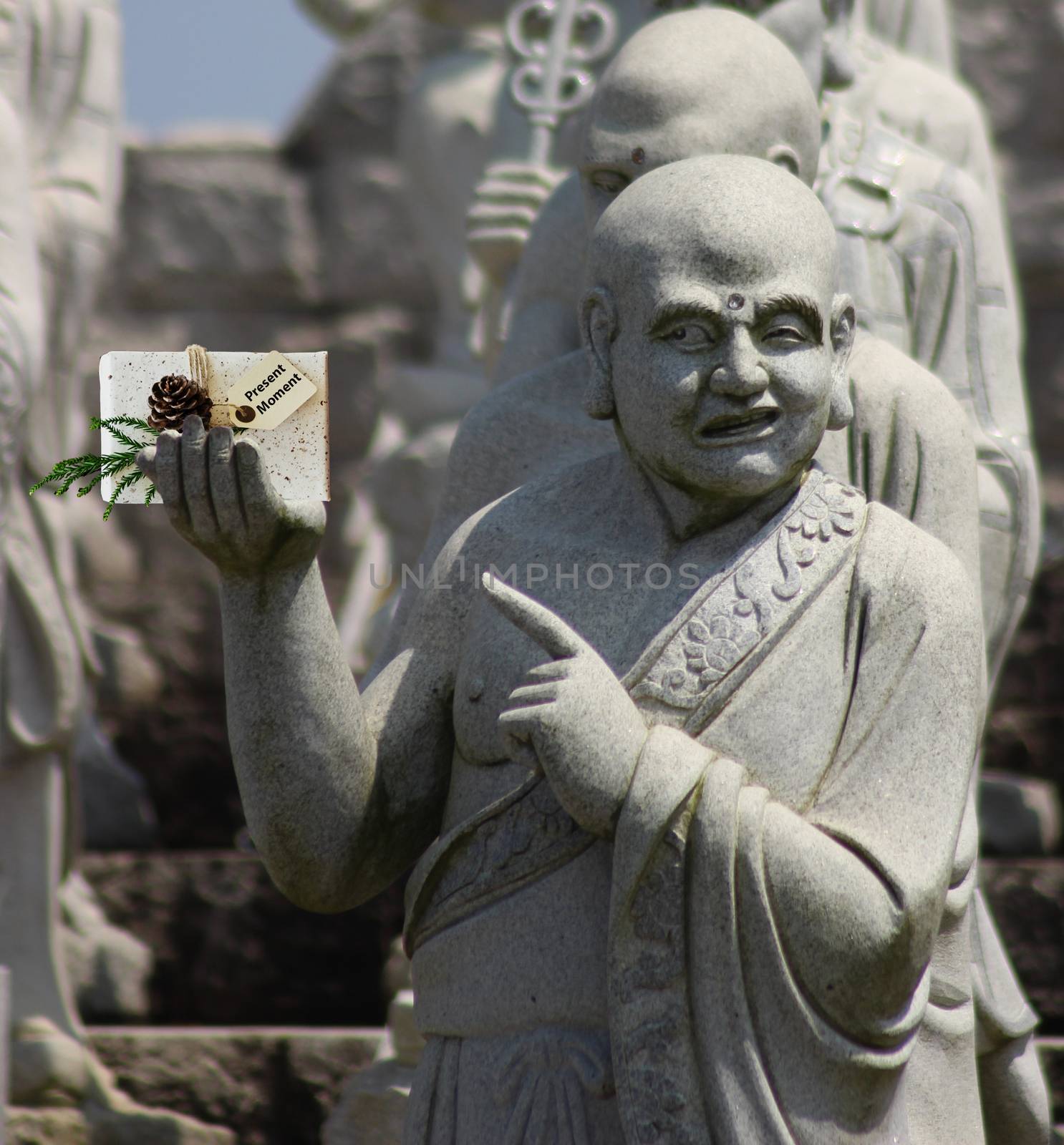 Christmas buddhist monk sculpture holding a present that says present moment and pointing at it