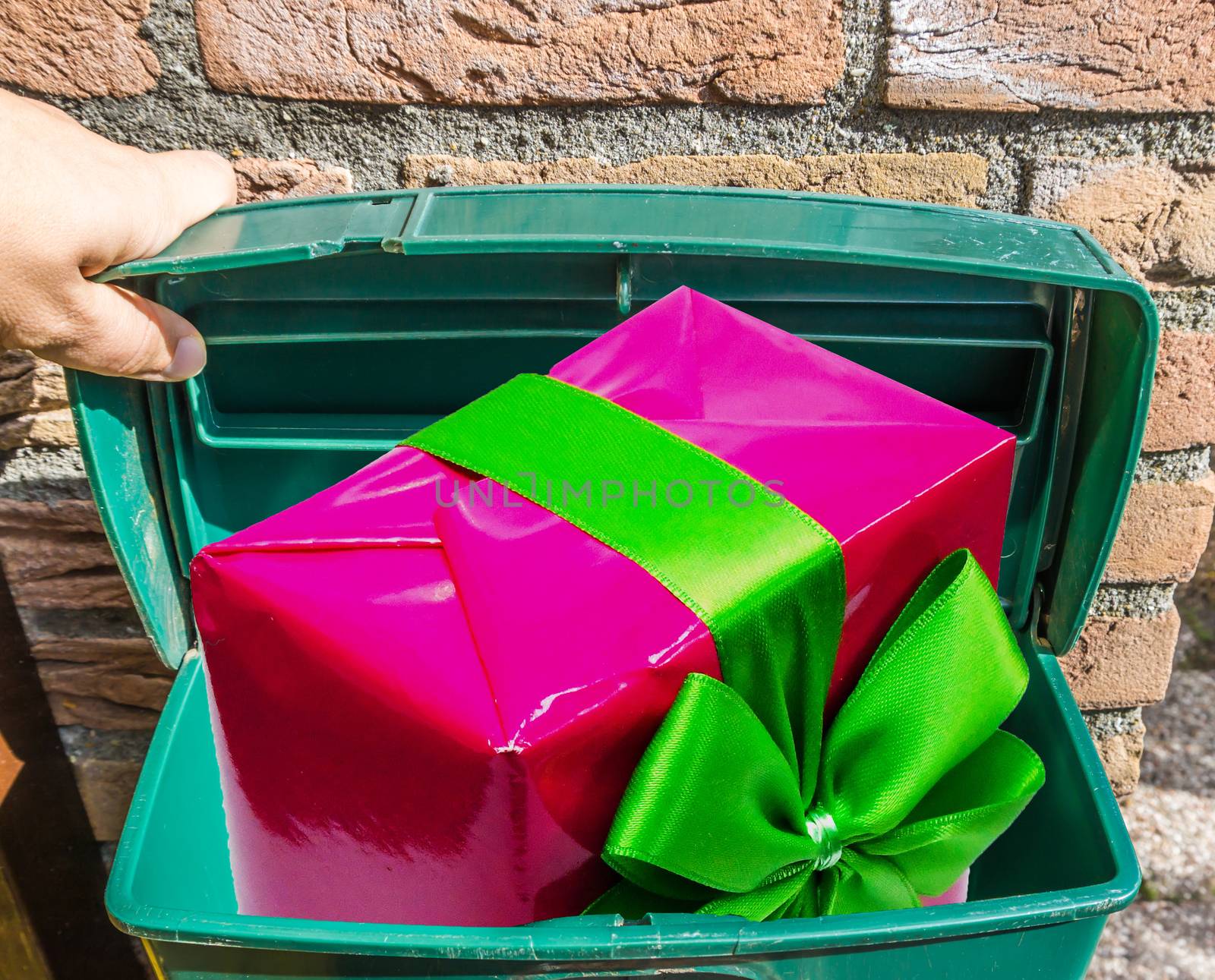 Big pink Christmas present with ribbon in a classic green mailbox