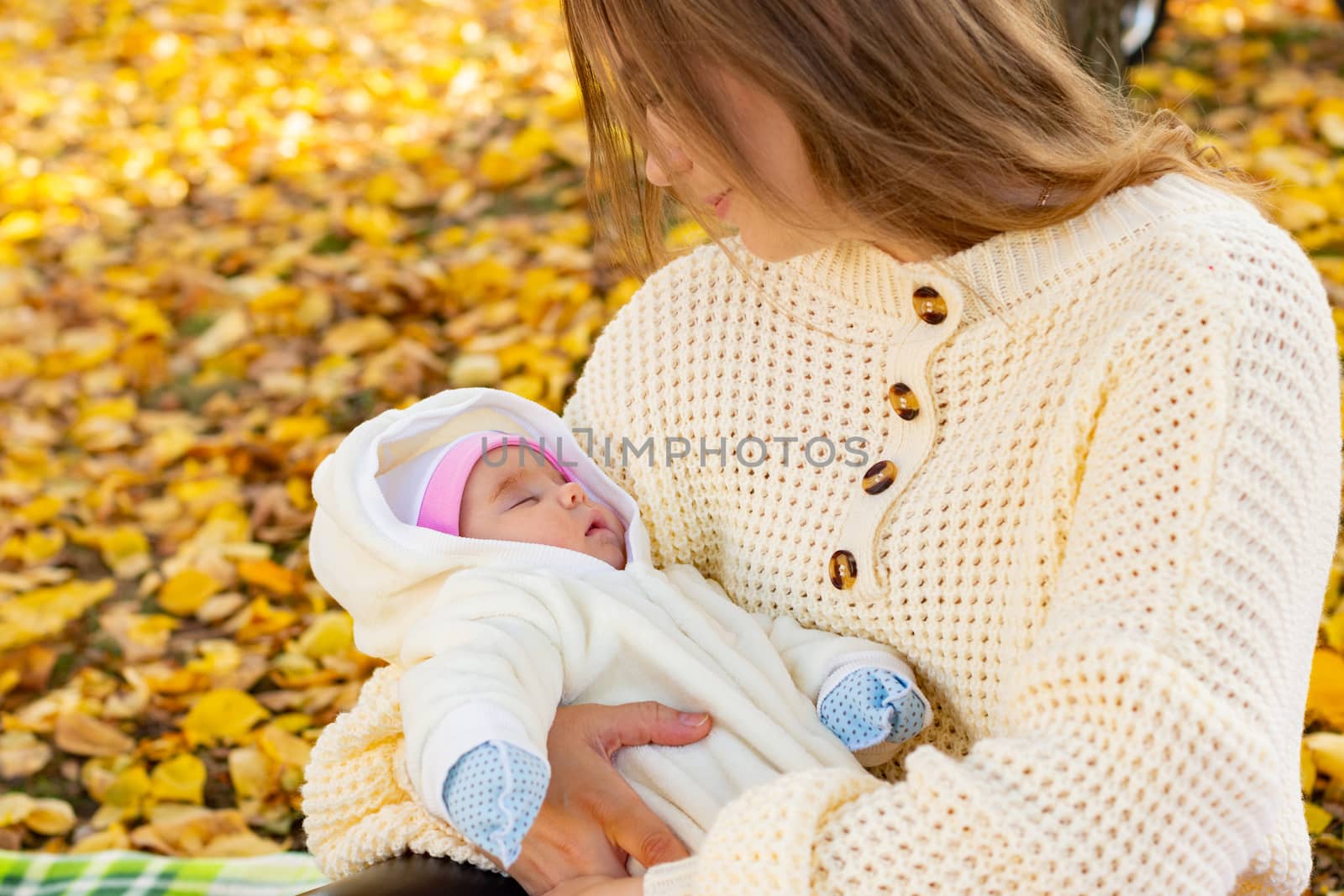 Mom holds baby in her arms on walk in autumn park