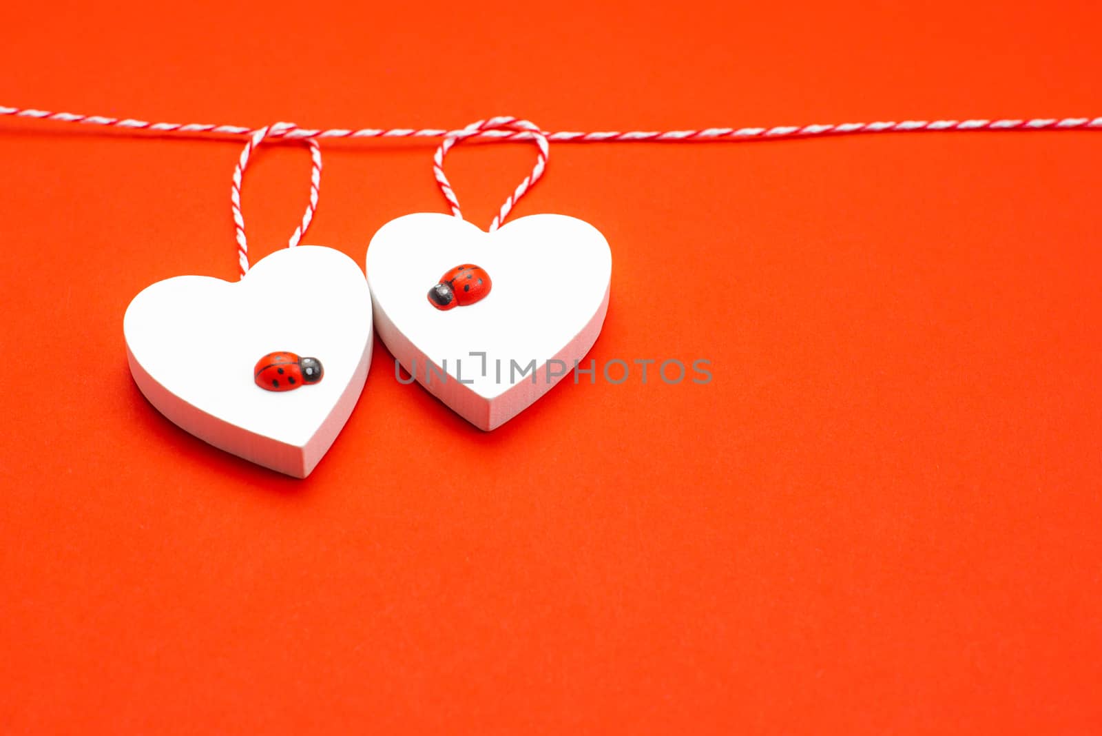 Blank for the designer. Valentines day concept. Greeting card. Copy space.Valentine's Day. White wooden hearts on a red background and red ladybugs.