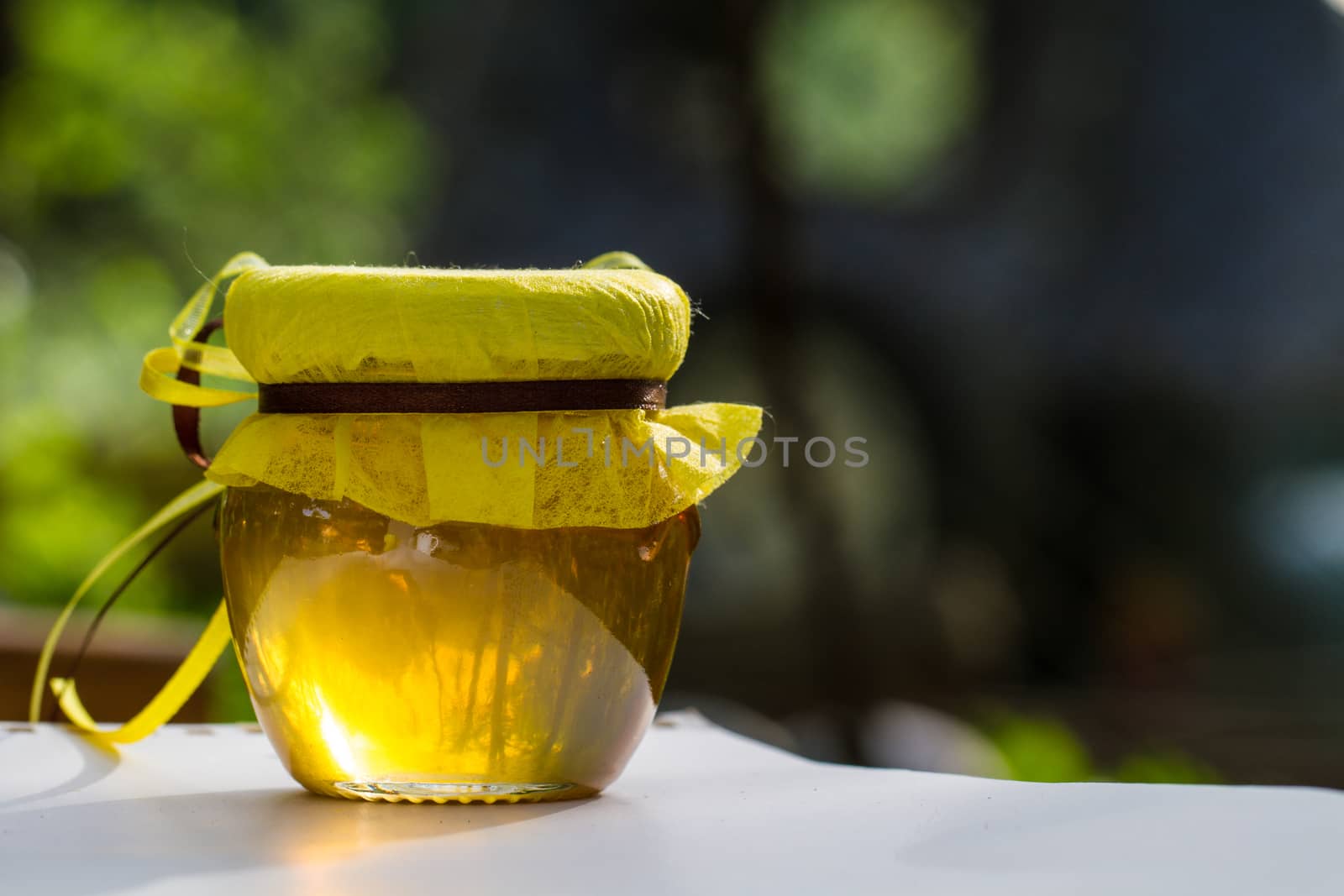 Jar with honey on table against nature background