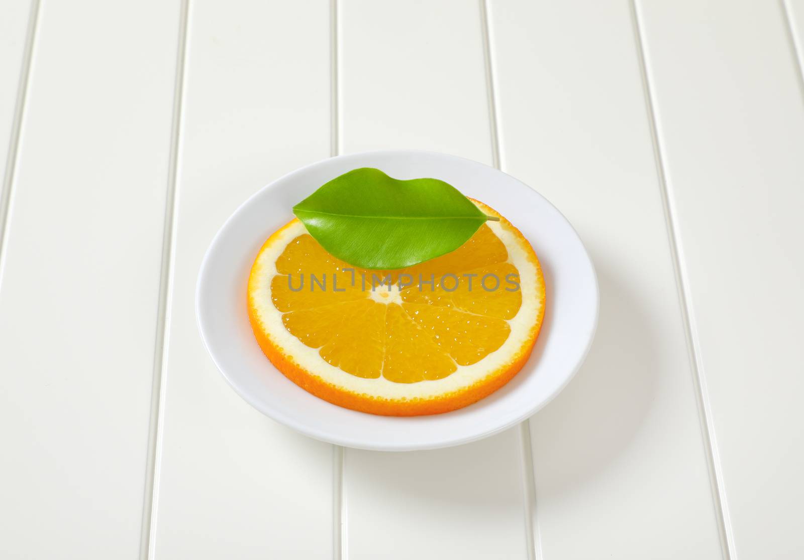 Thin slice of fresh orange on white plate