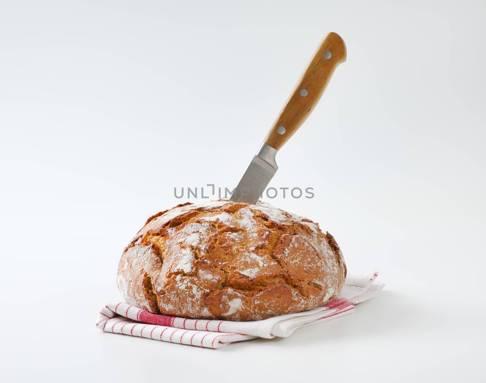 Loaf of rustic bread with a knife stuck in it