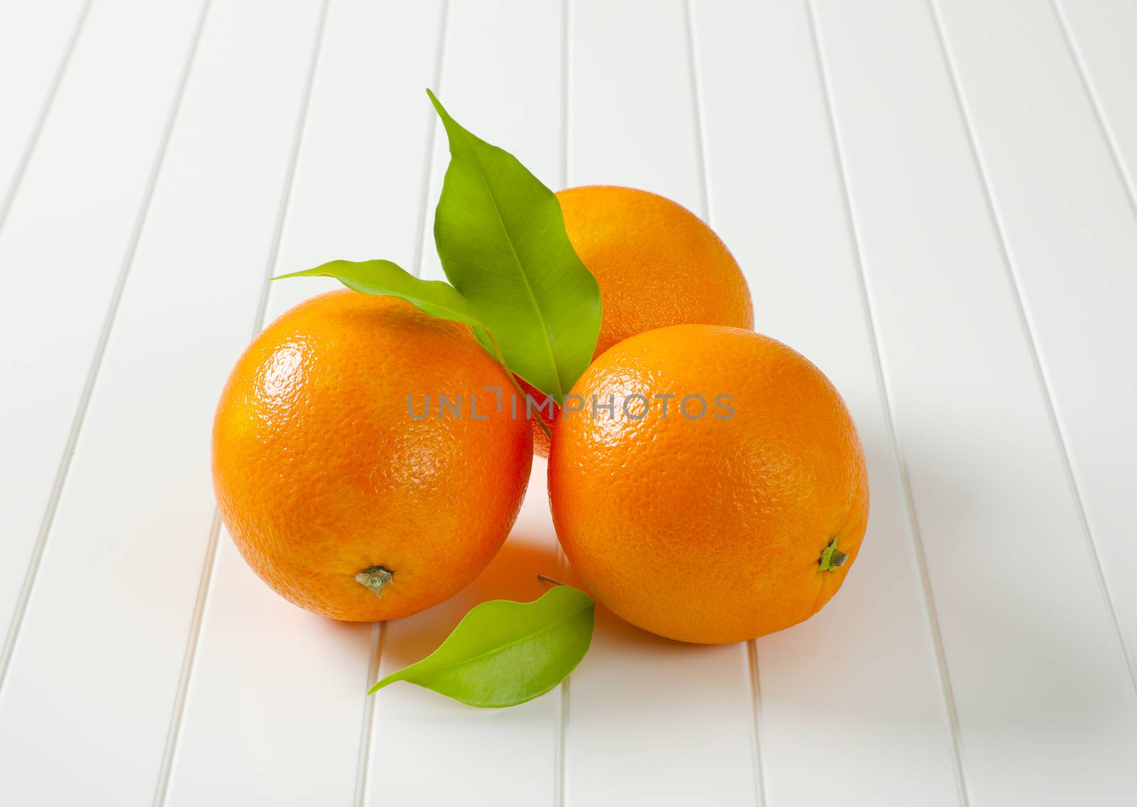 Three whole ripe oranges and leaves