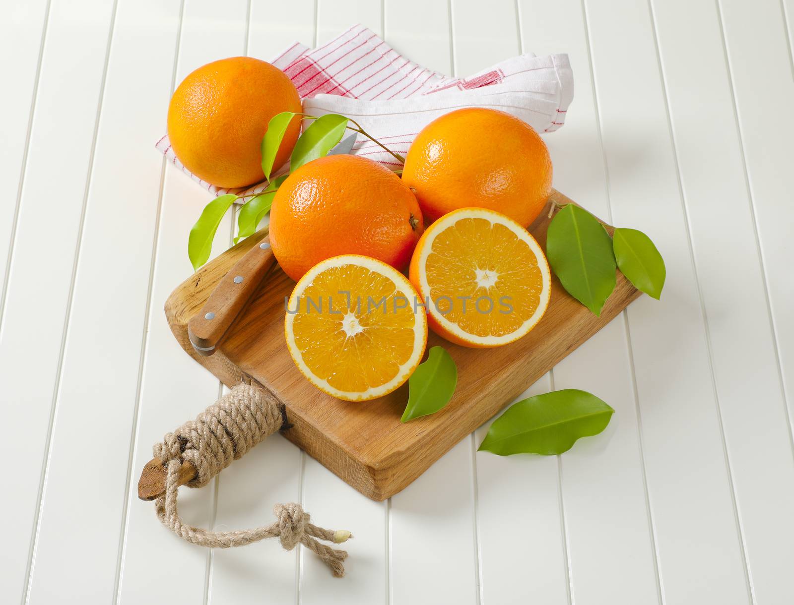 Whole ripe oranges and two halves on cutting board