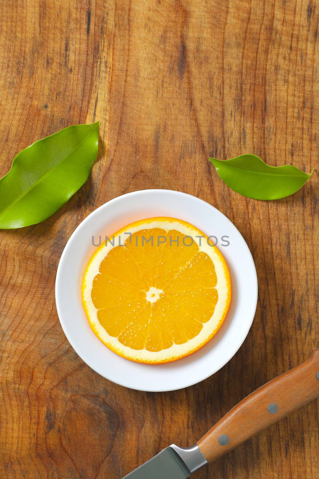 Thin slice of fresh orange on white plate