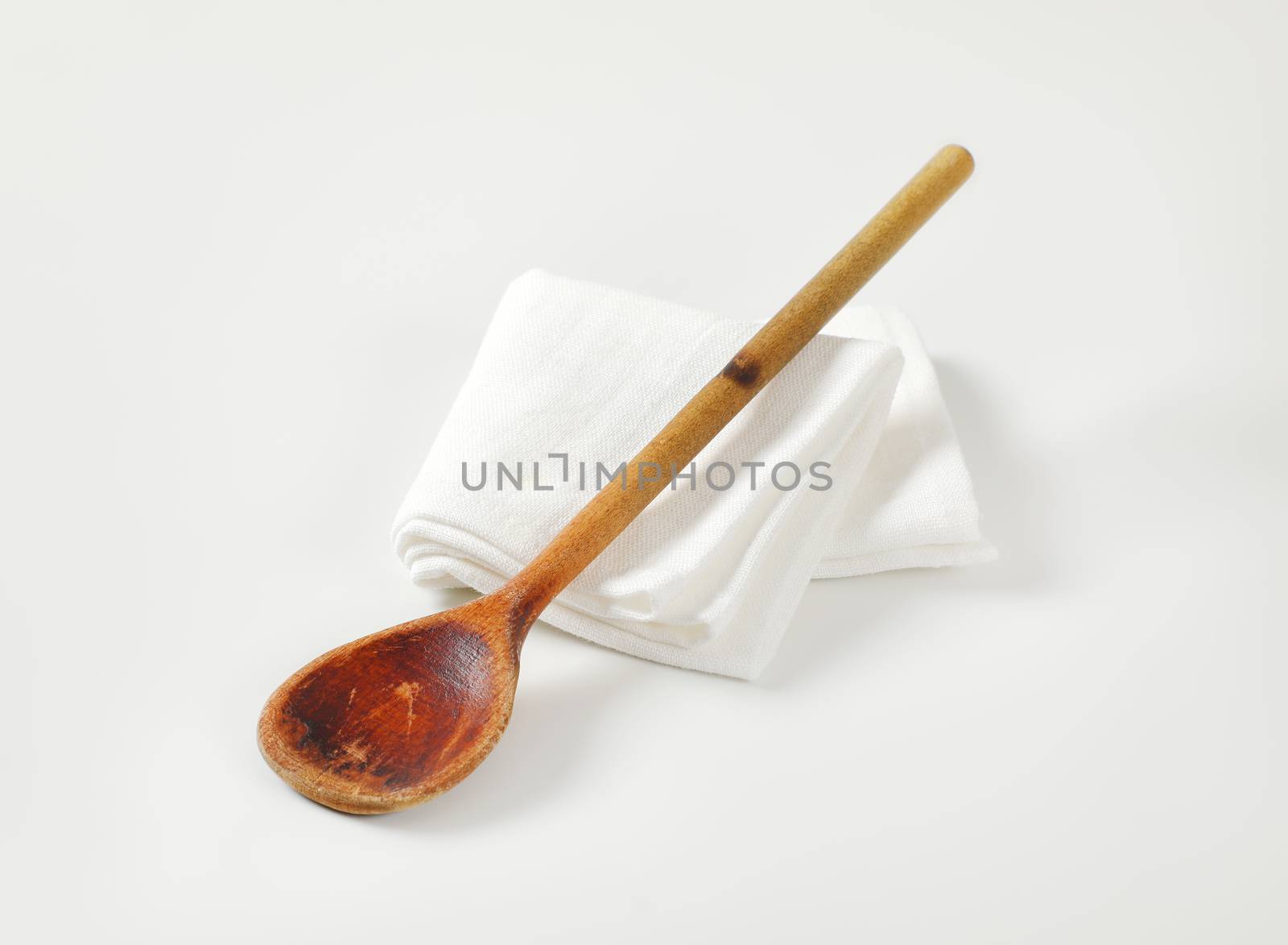 Old wooden cooking (stirring) spoon on white napkin