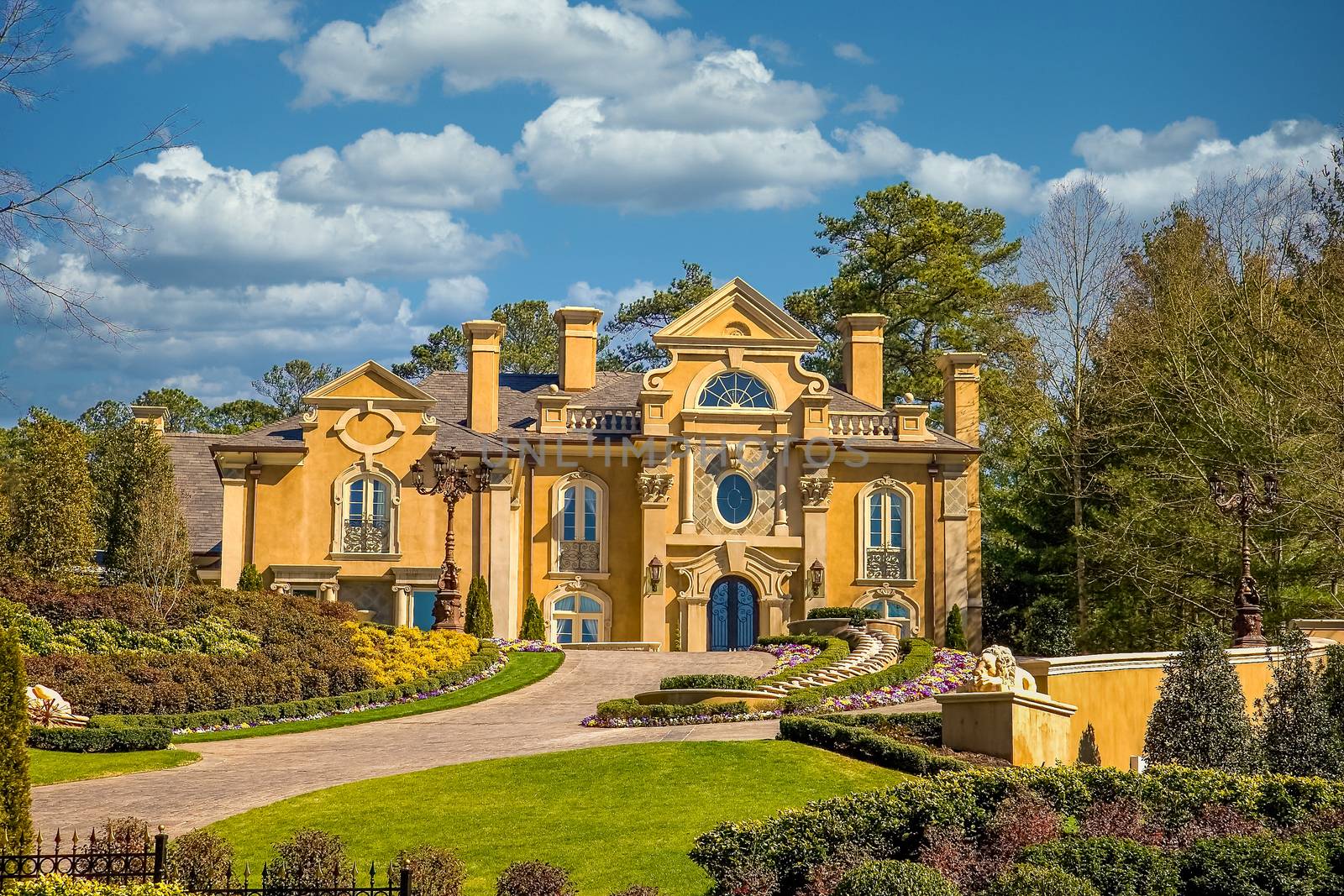 A large stucco mansion high on a manicured and landscaped lawn