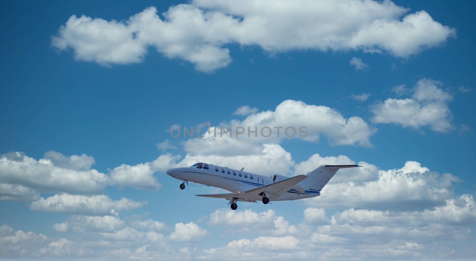 A small private jet ascending through the sky and clouds