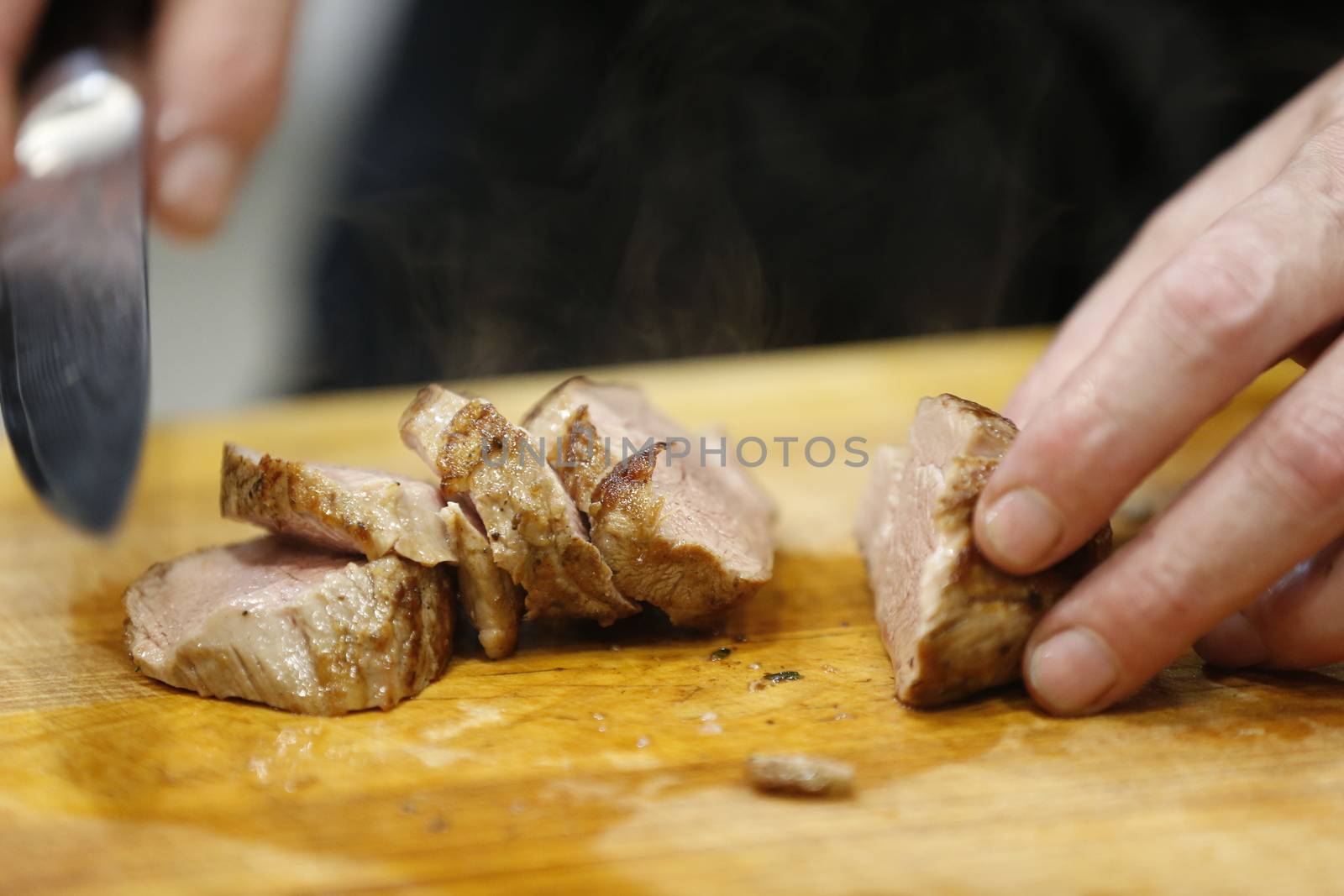 RoastedKnife cuts cooked hot meat.Cut the fried meat. Ready meat. Ready-made hot meat. Meat with smoke meat on a baking pan.