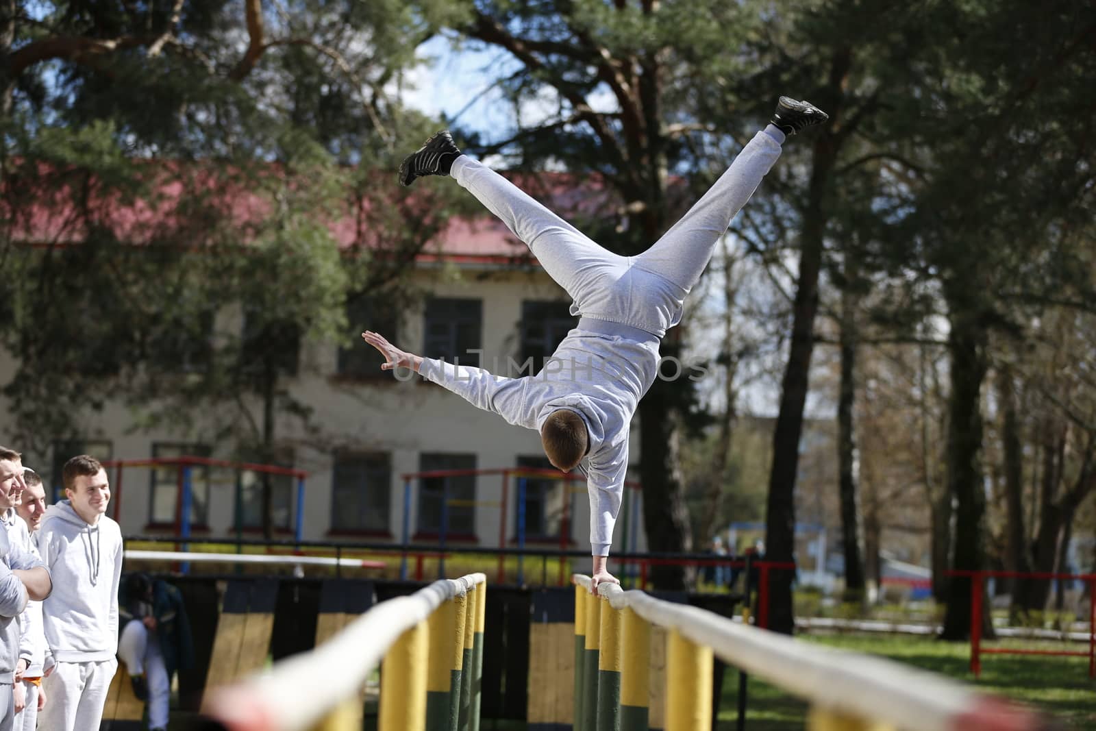 On the crossbeam on one hand.Do sport. Sports lesson. Gymnastics for students. Sports training of soldiers in the army