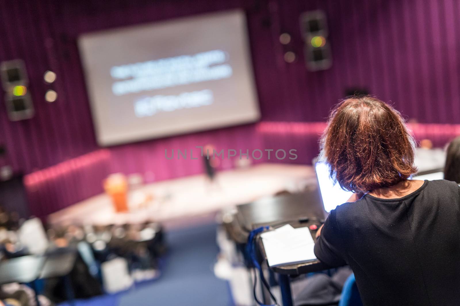 Conference and Presentation. Audience at the conference hall. Business and Entrepreneurship. Faculty lecture and workshop. Focus on unrecognizable person in audience making notes on laptop.