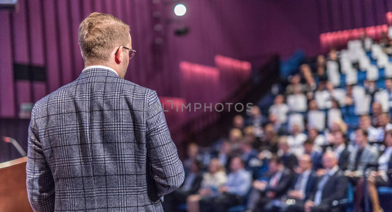 Speaker giving a talk on corporate business conference. Unrecognizable people in audience at conference hall. Business and Entrepreneurship event.