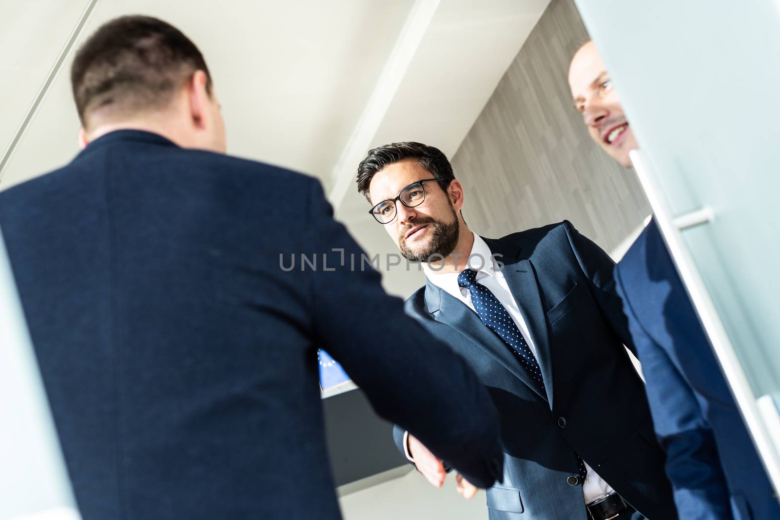 Group of confident business people greeting with a handshake at business meeting in modern office or closing the deal agreement by shaking hands. by kasto