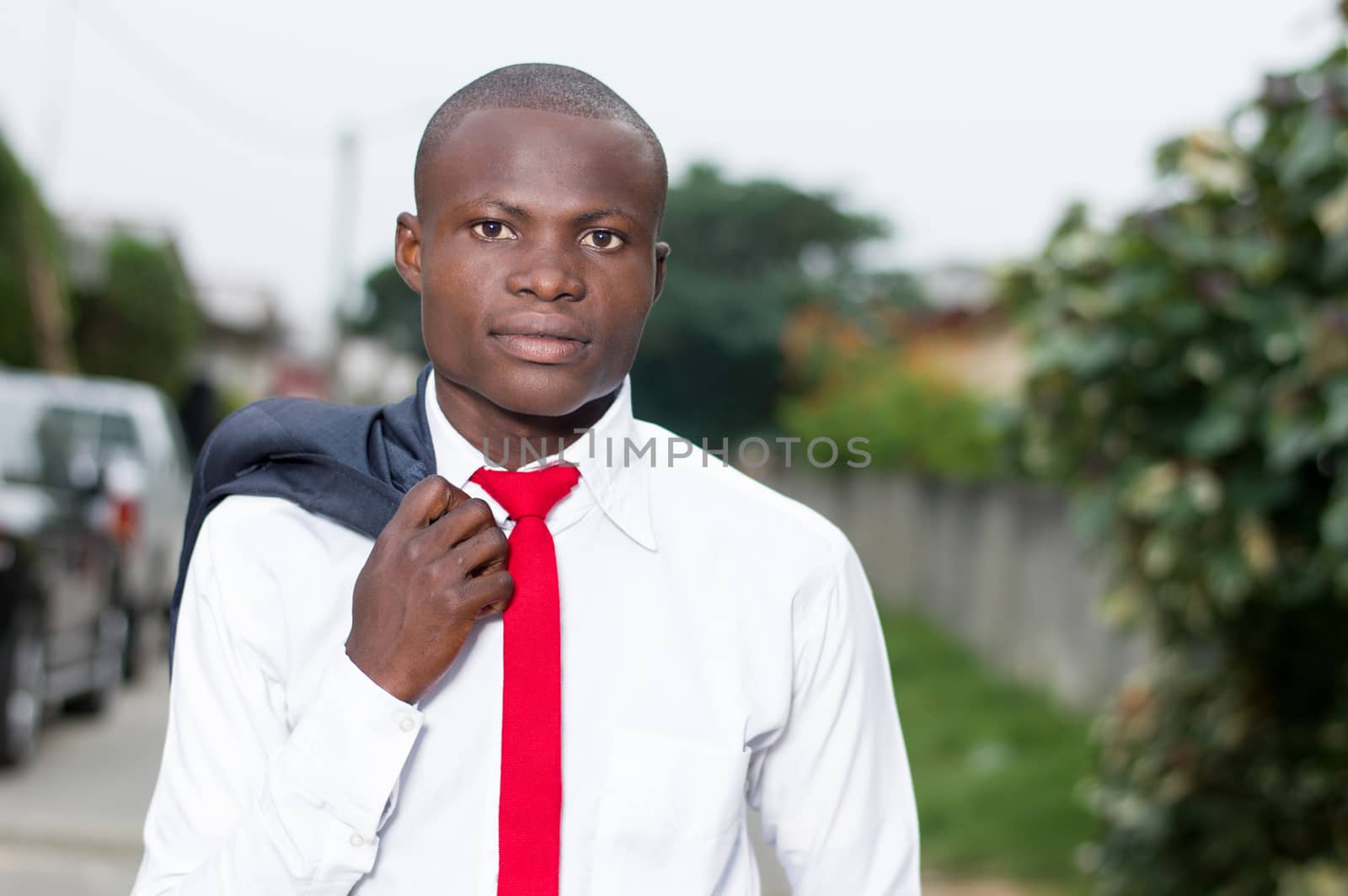 Portrait of young African businessman with his jacket on his shoulder.