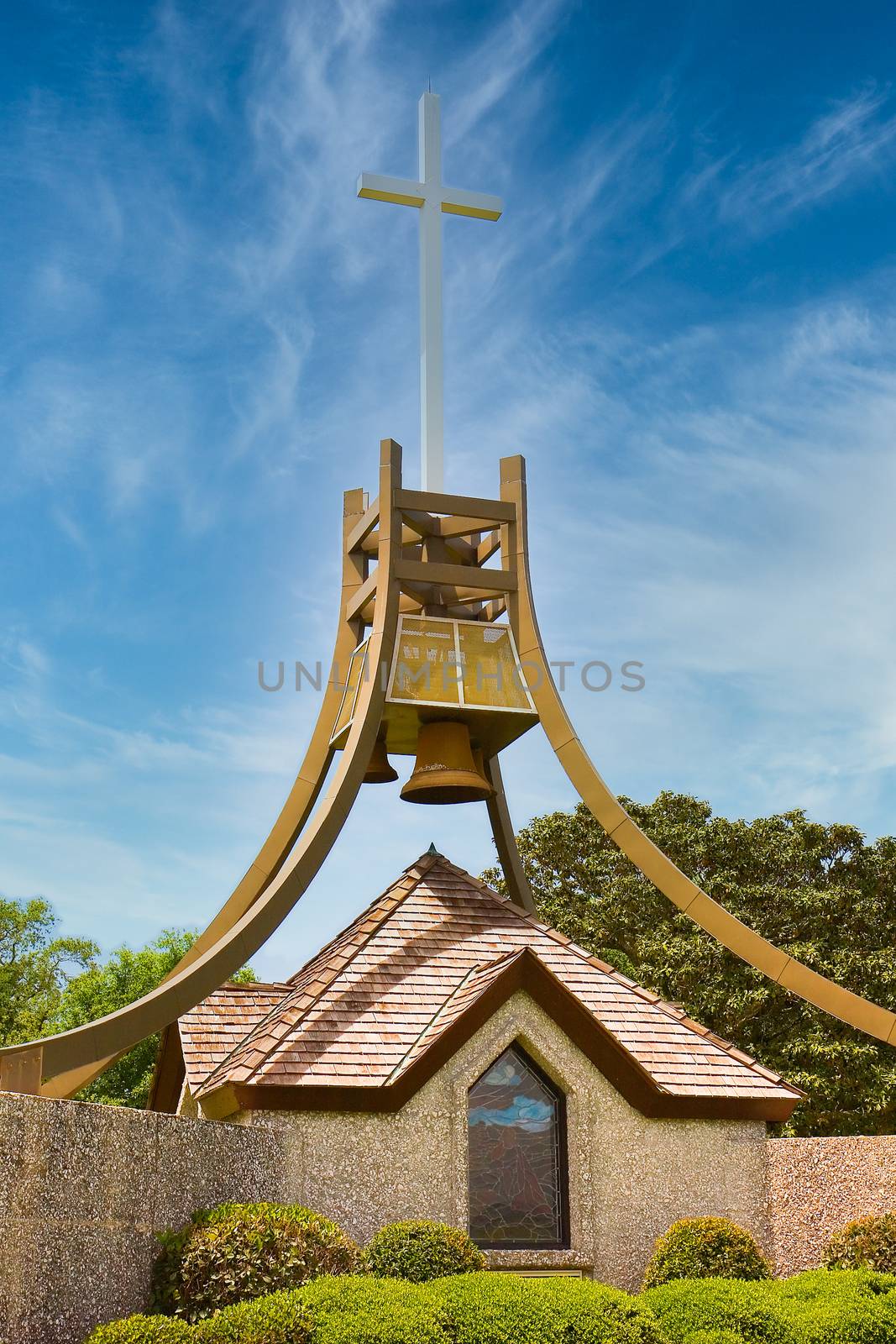 A bell tower and a cross on a display in a public park