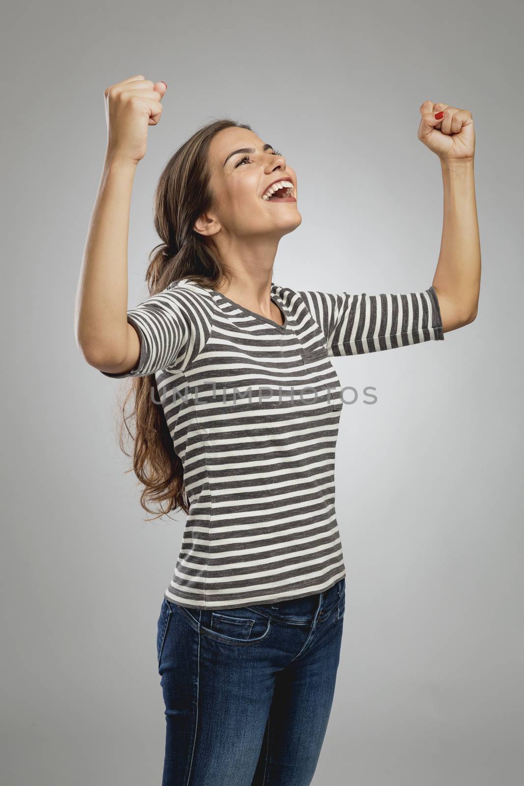 Portrait of a beautiful and successful young woman with raised arms