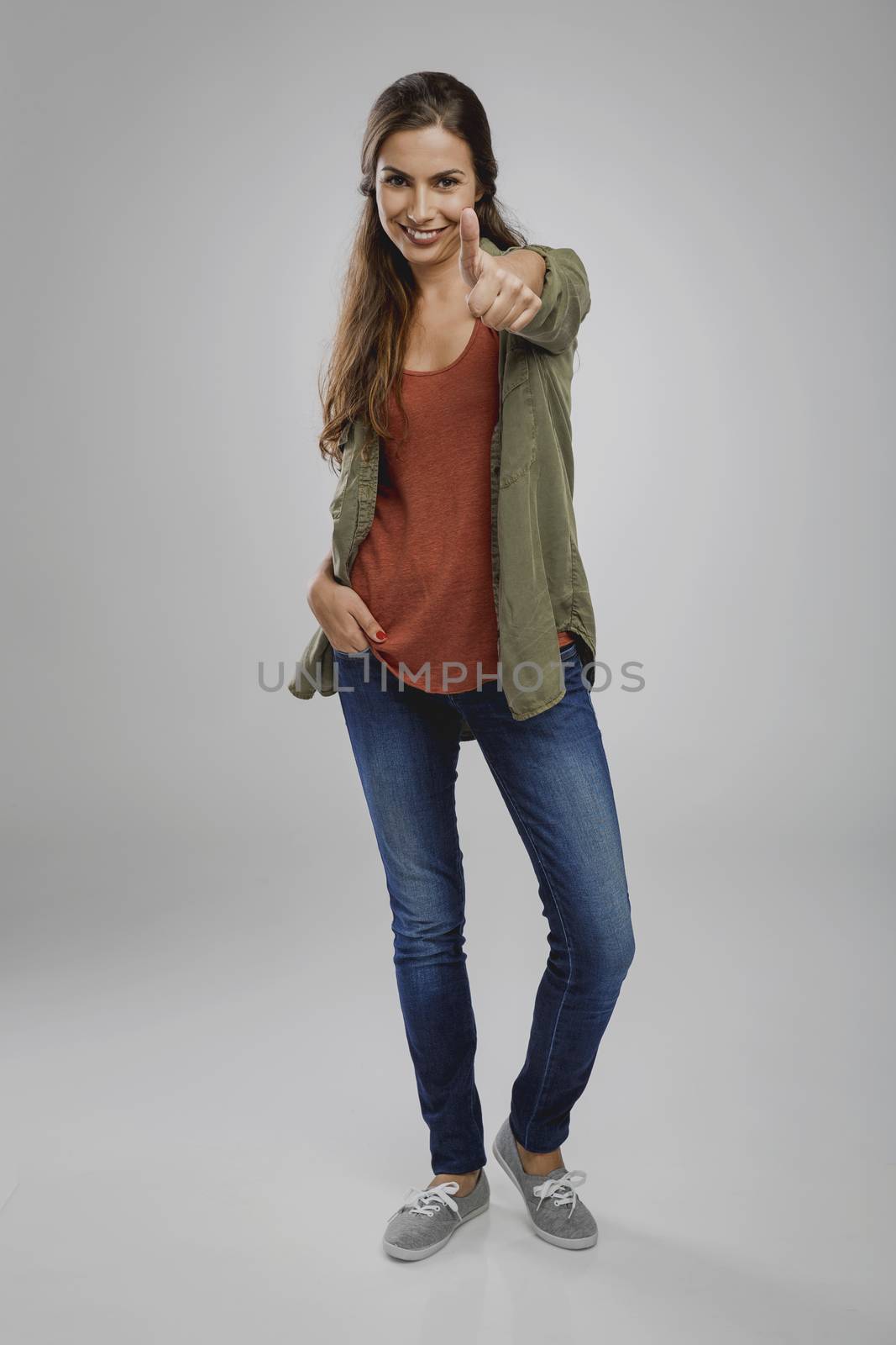 Beautiful woman over a gray background with thumbs up