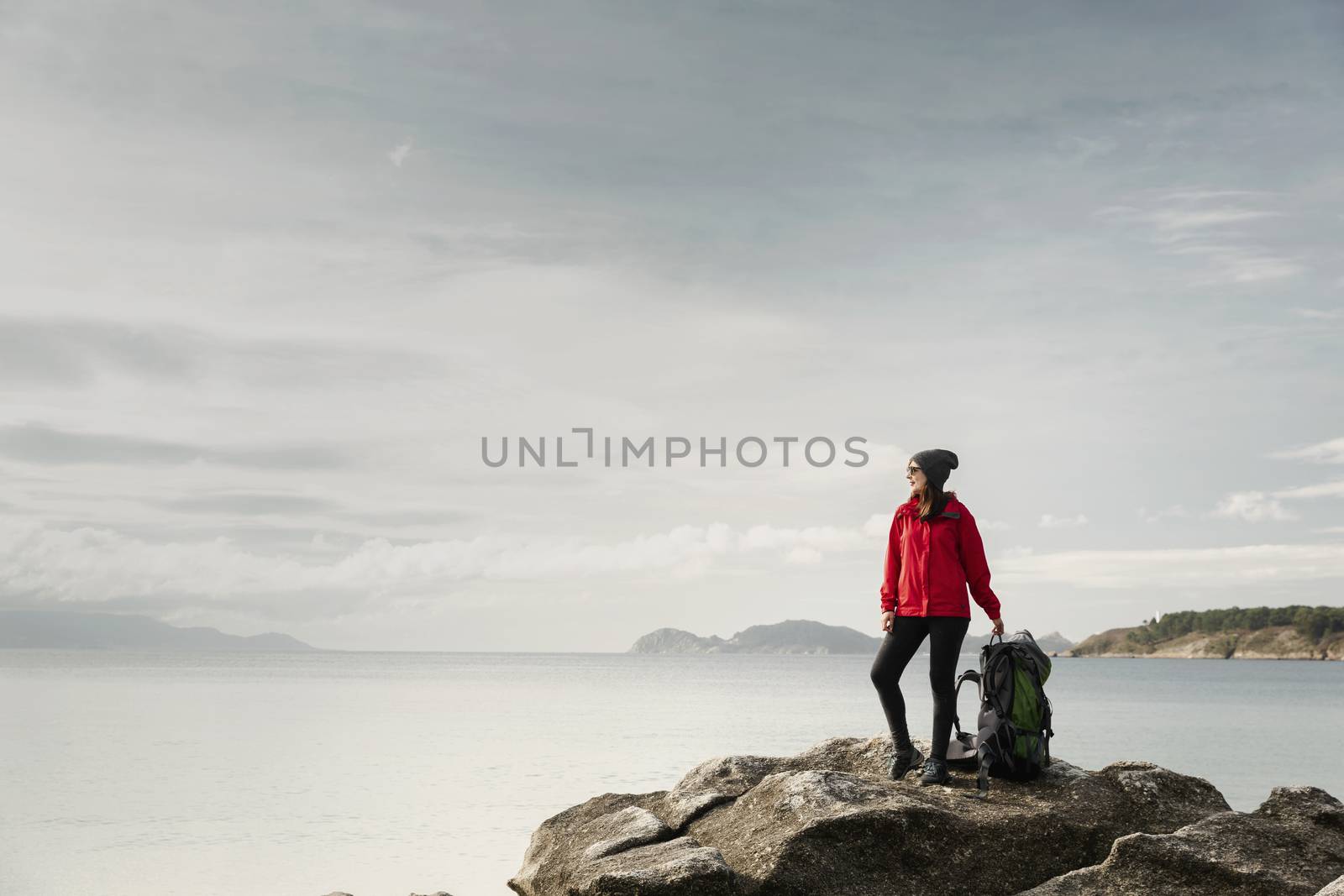 Woman with backoack enjoying the morning view of the coast