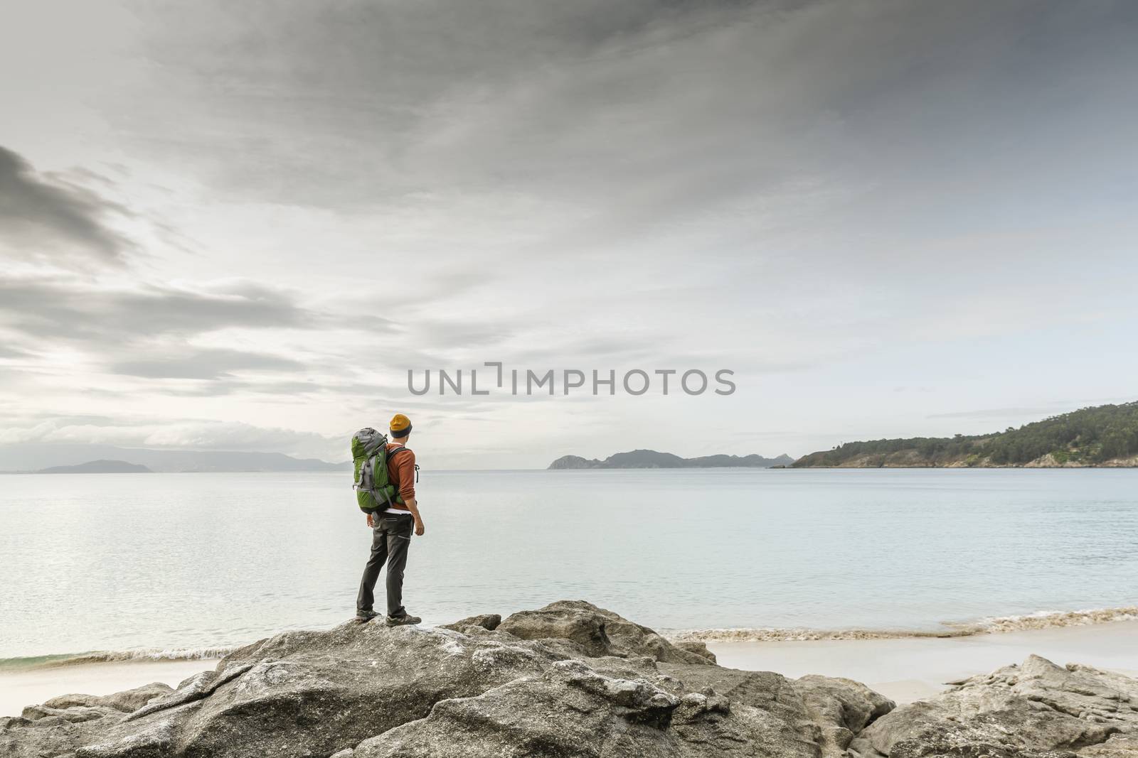 Man with backoack enjoying the morning view of the coast