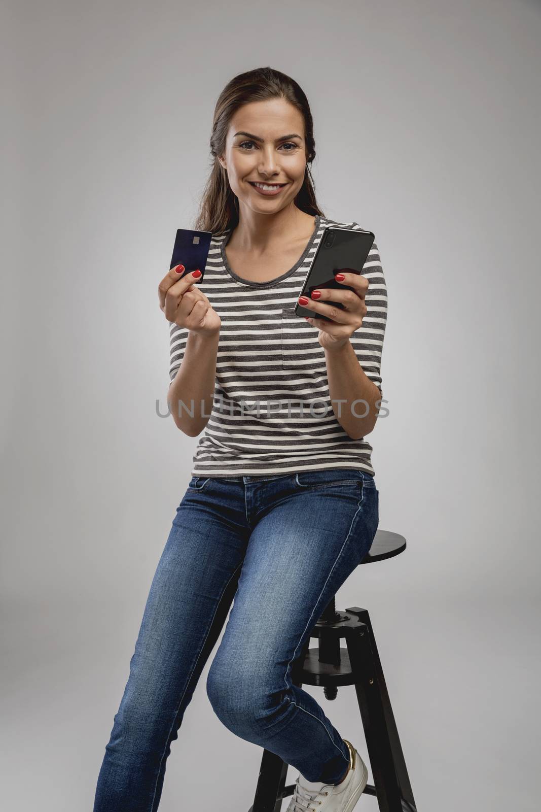 Beautiful happy young woman sitting on a bench and shopping online