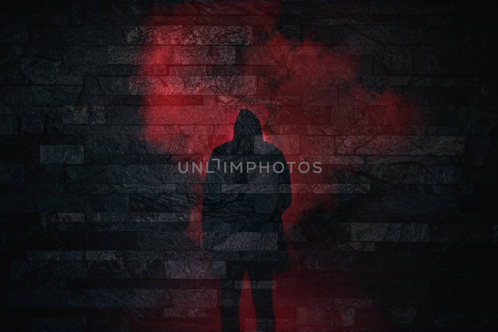 Halloween scary silhouette of a person standing in red smoke on a brick wall background