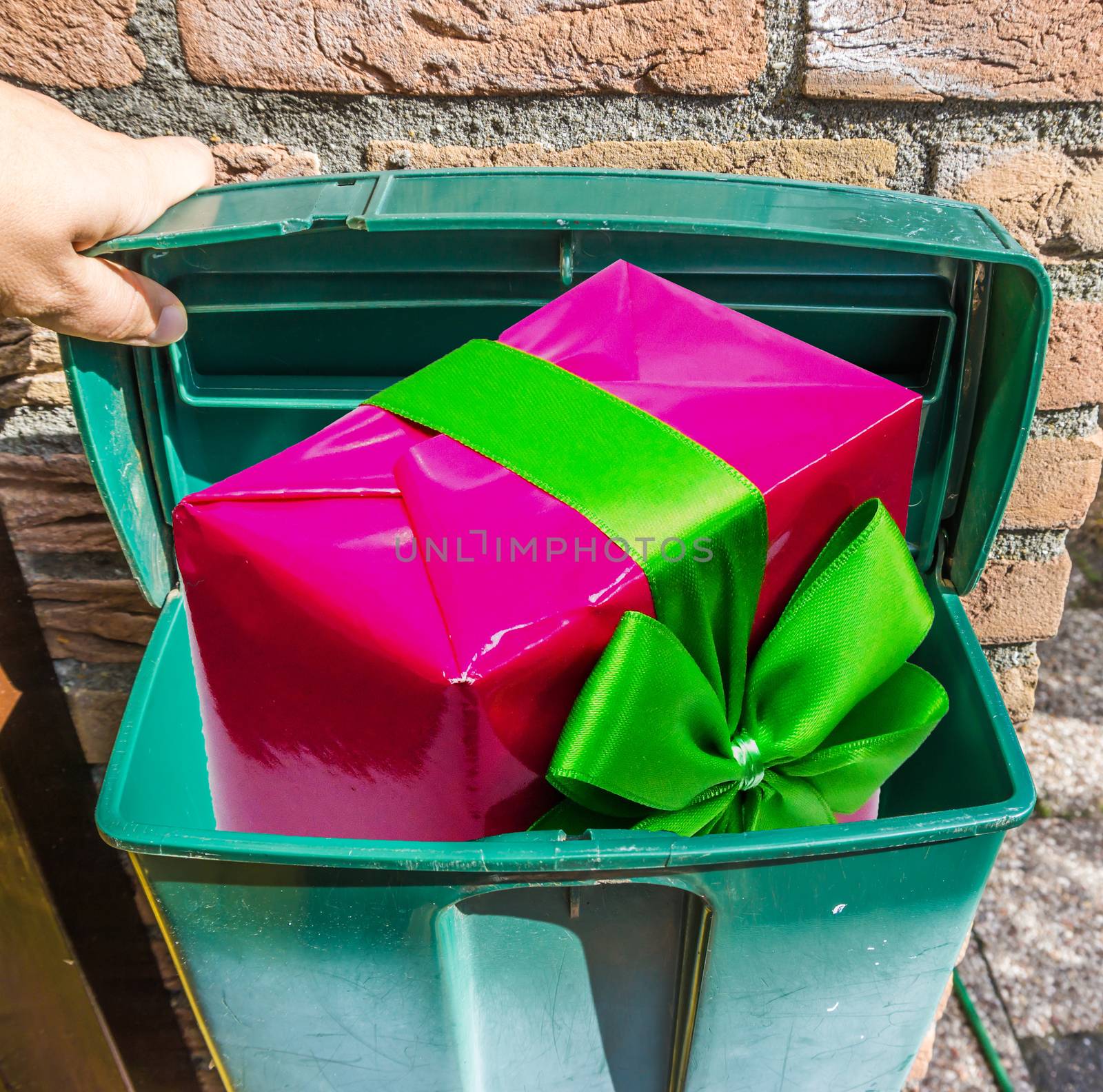 pink christmas present with green ribbon in a classical green mailbox