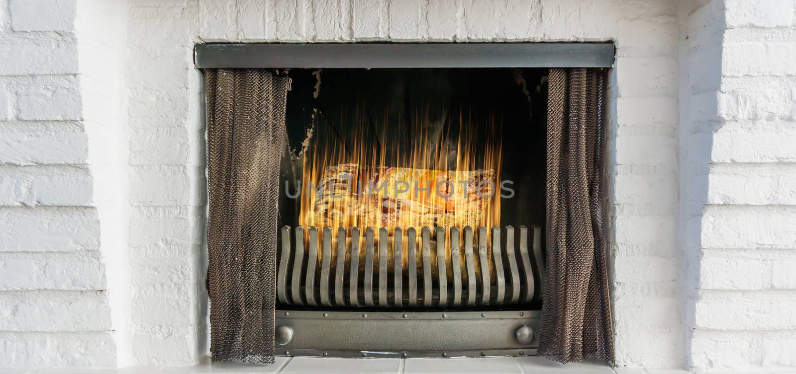 Burning fireplace with iron curtains in closeup winter background