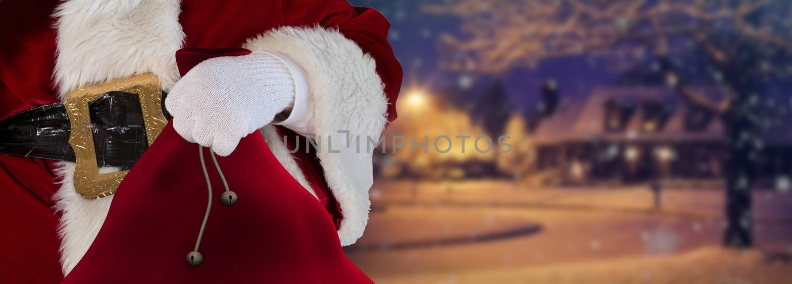 Santa claus holding his bag standing on the snow white streets with a house in the distance christmas background