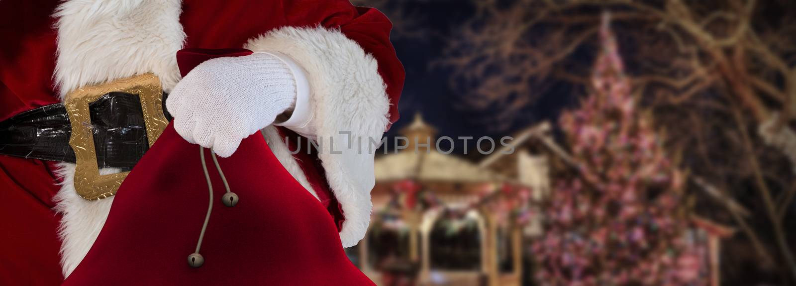 Christmas concept santa claus standing in a decorated town holding his sack full of gifts by charlottebleijenberg