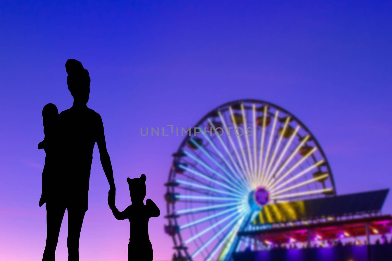 Family silhouette in a theme park looking at the ferris wheel mother with her little daughter and baby