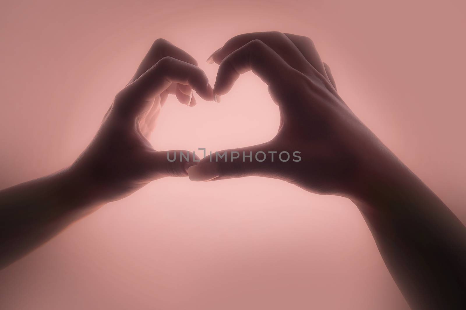 Woman hands making a heart shape on a mood background