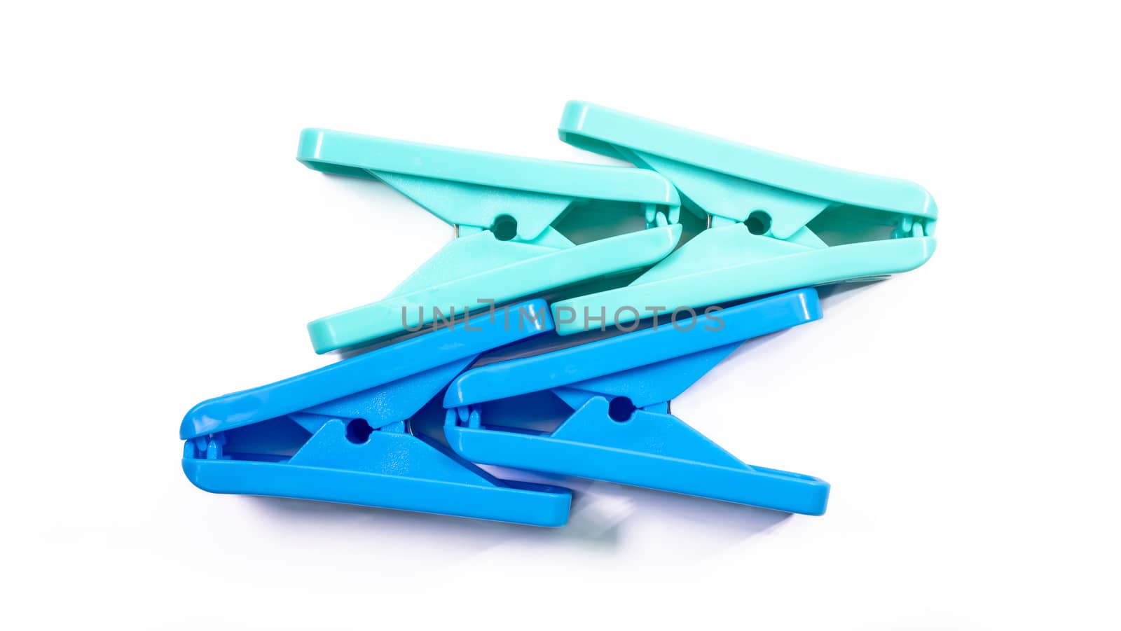 The close up of light green clothes peg and blue clothes peg on white background.