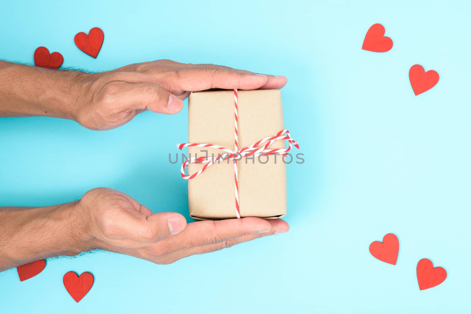 Valentine's Day Concept, Top view Flat lay, have red heart and hand holding gift box on blue background with copy space for your text