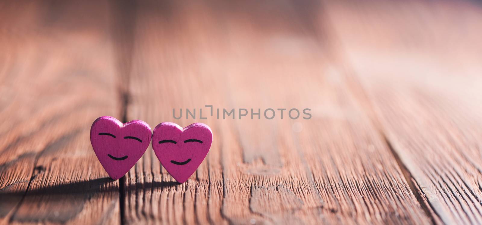 Two pink smiling hearts on wooden background with copy space for text