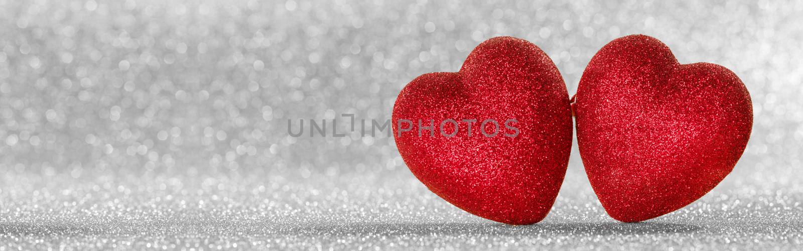 Two red glitter hearts on bright silver lights bokeh background Valentines day card