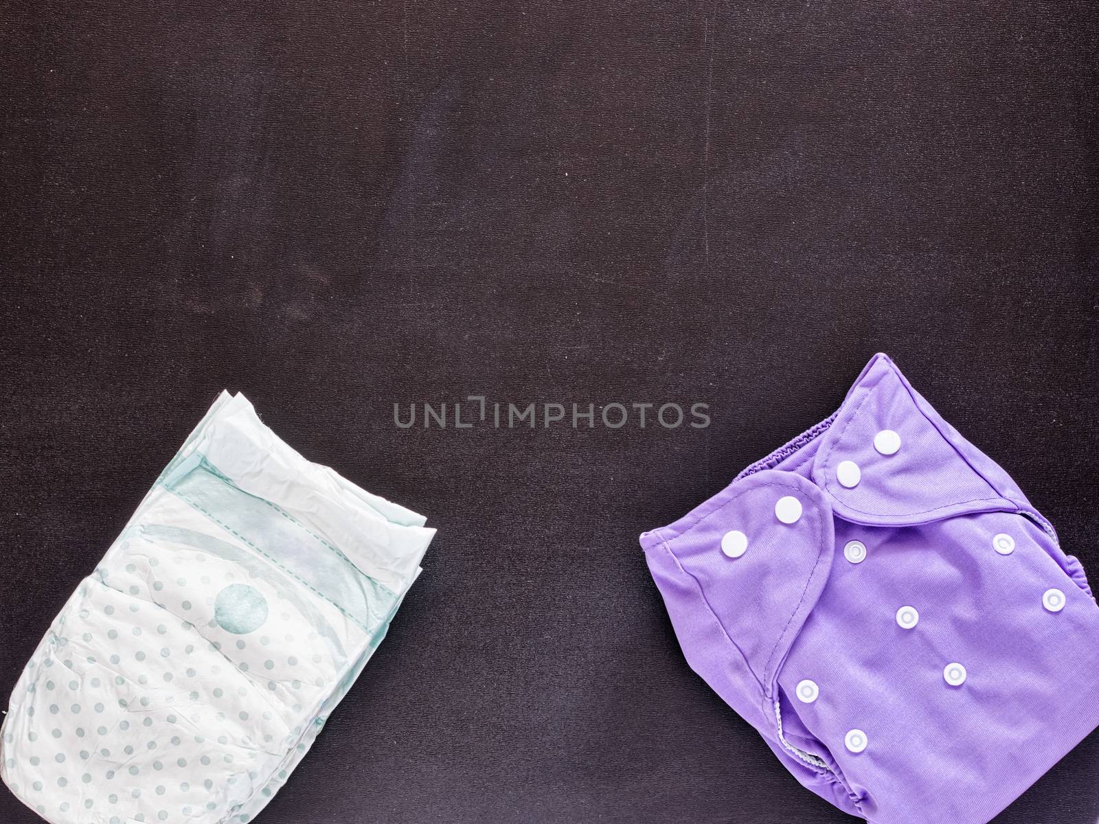cloth diaper and disposable diaper on dark background with copy space. cloth and disposable diapers top view or flat lay