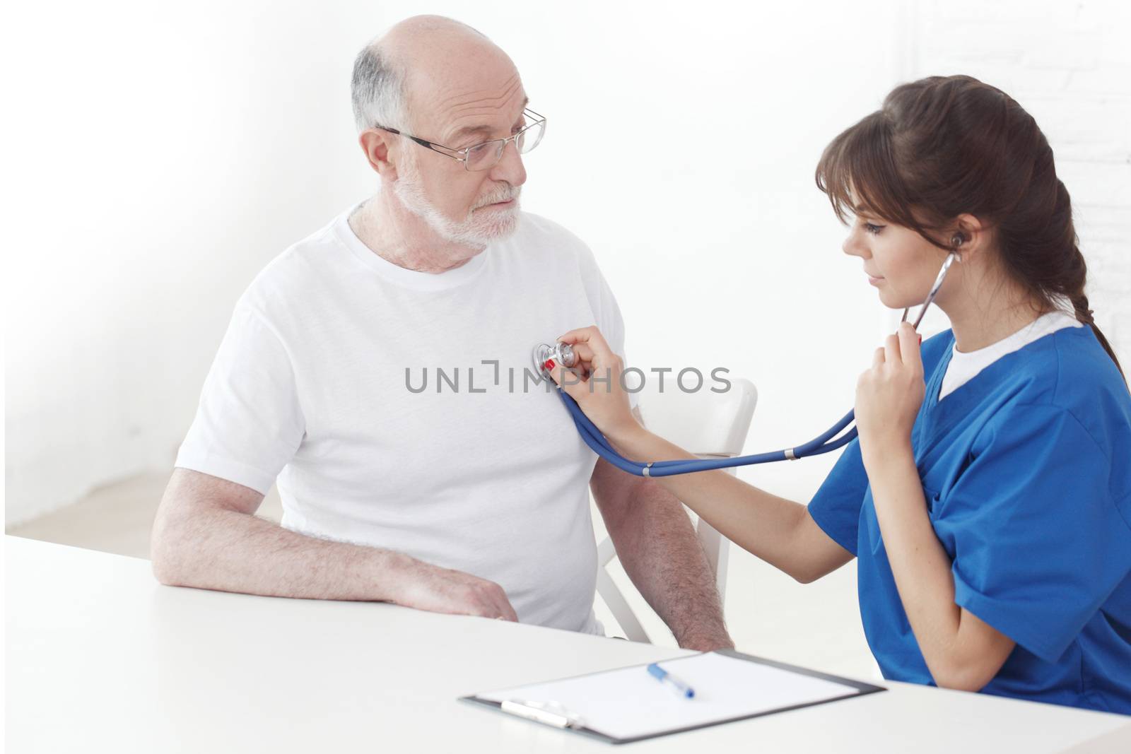 Doctor listening to senior man heartbeat by ALotOfPeople