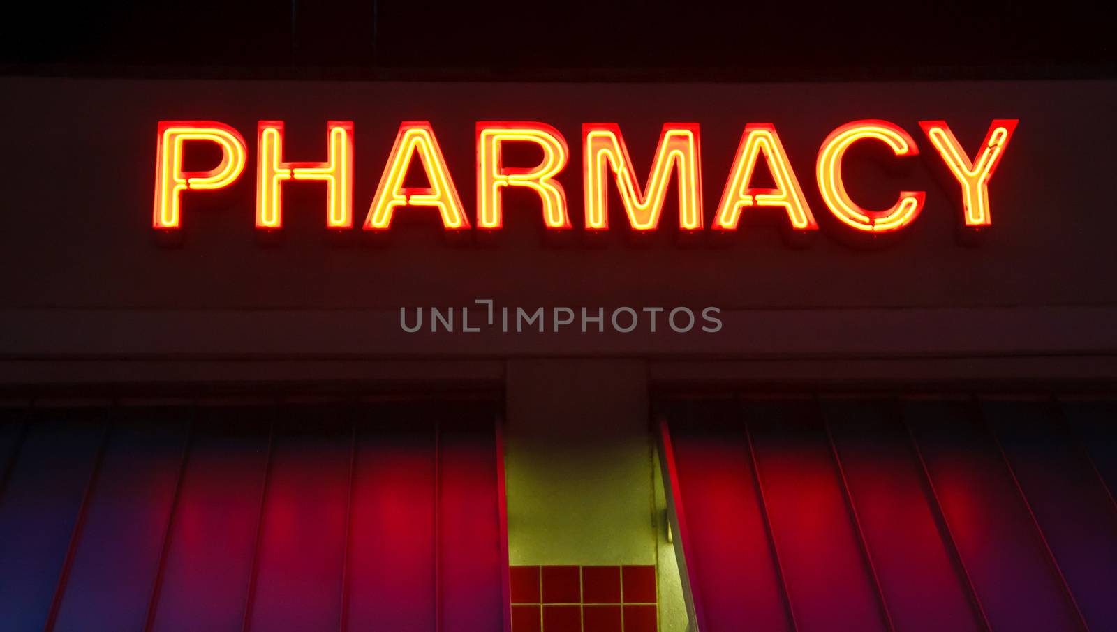 A neon sign over a pharmacy on a roof