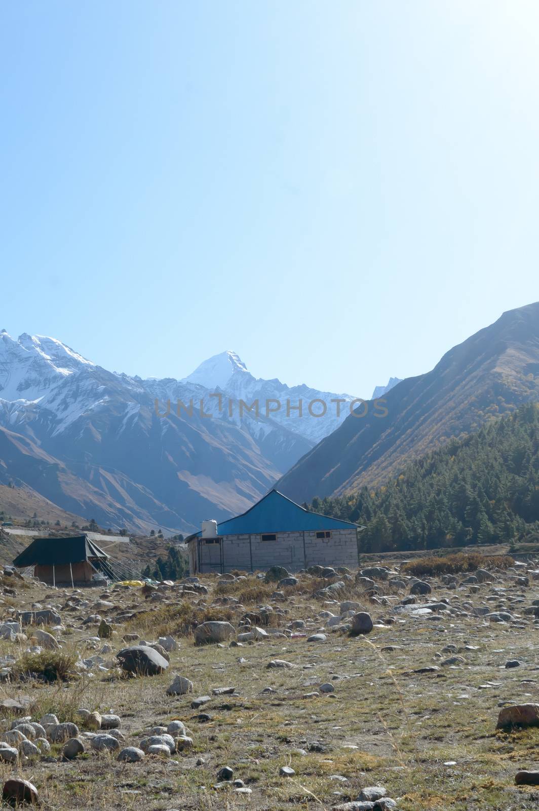 A mountain Alpine hut cabin in high Himalayas mountains, located to provide shelter to mountaineers, climbers and hikers. An interlocking overlapping spur hill ridges V-shaped valley in background. by sudiptabhowmick