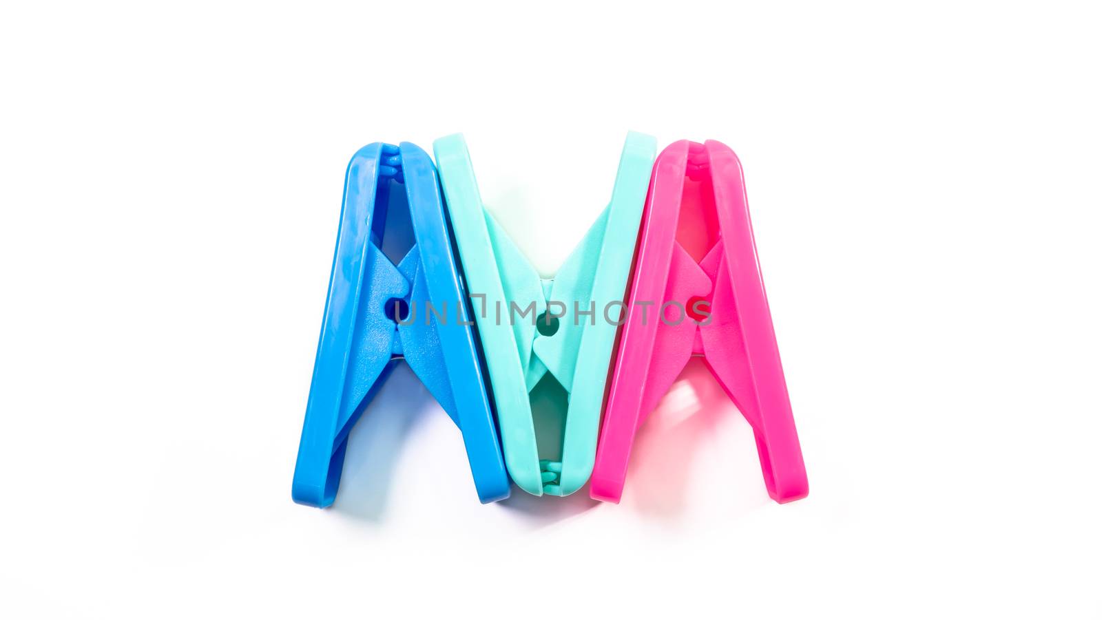 The close up of light green clothes peg and blue clothes peg and pink clothes peg on white background.