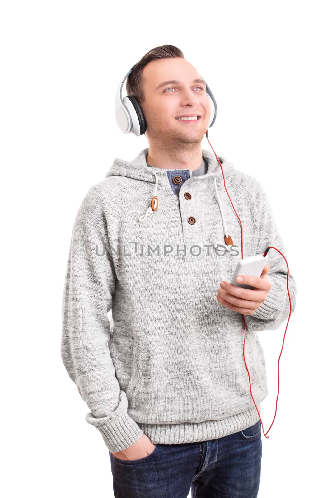 Music concept. Handsome casual young man with white headphones listening to music on his phone, enjoying and smiling, isolated on white background. Young man listening to music on his headphones.