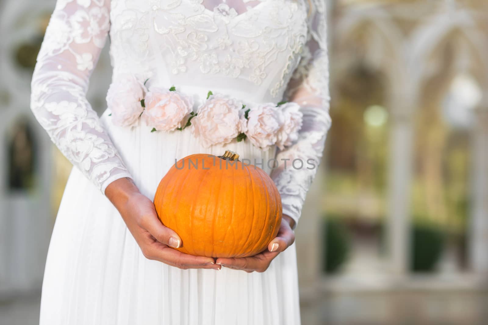 Bride holding pumpkin in her hands by HERRAEZ