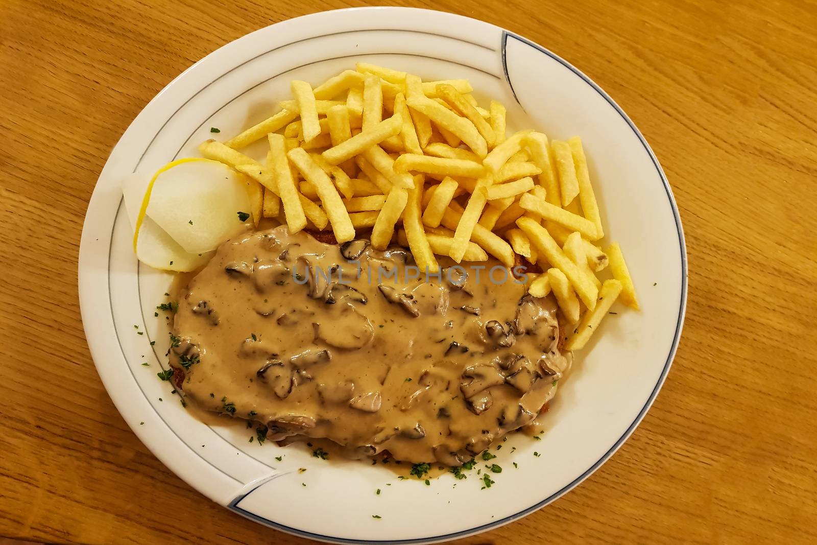 Jaeger Viennese schnitzel with French fries and mushrooms close-up on a plate. horizontal top view from above