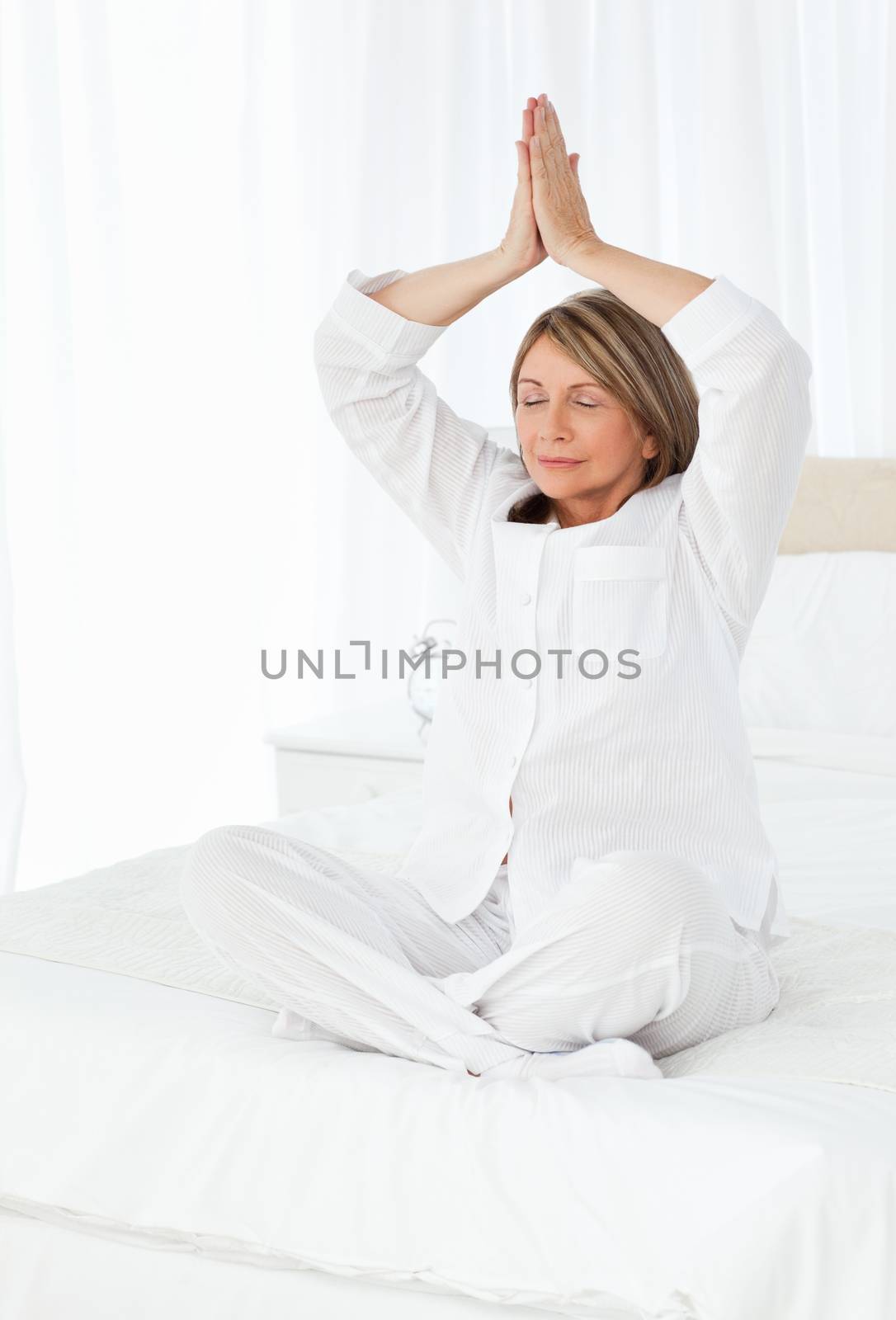 Senior practicing yoga on her bed at home