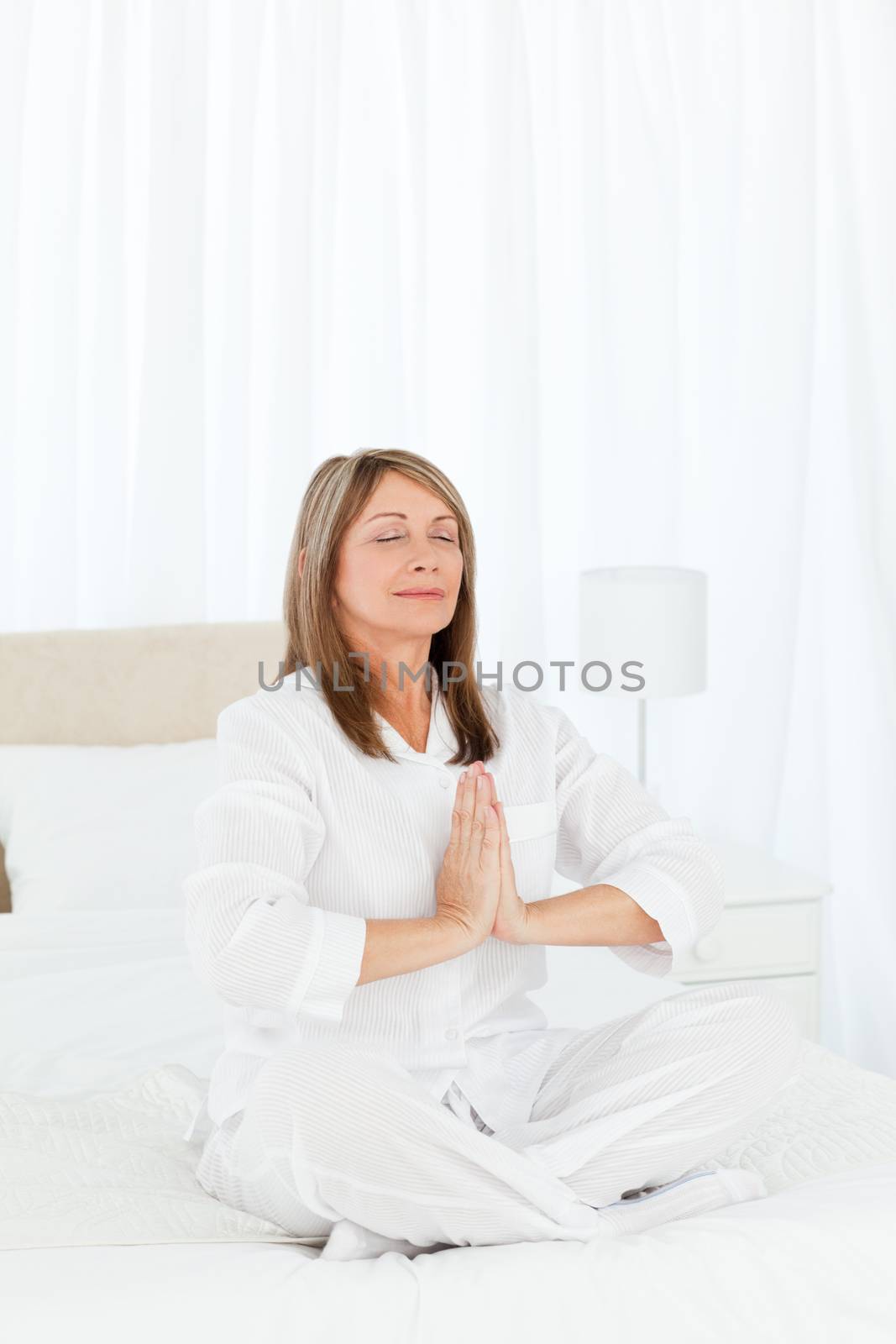 Senior practicing yoga on her bed at home