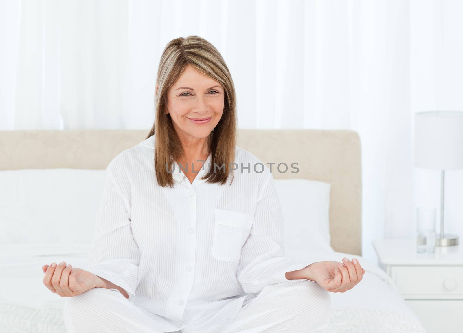 Senior practicing yoga on her bed by Wavebreakmedia