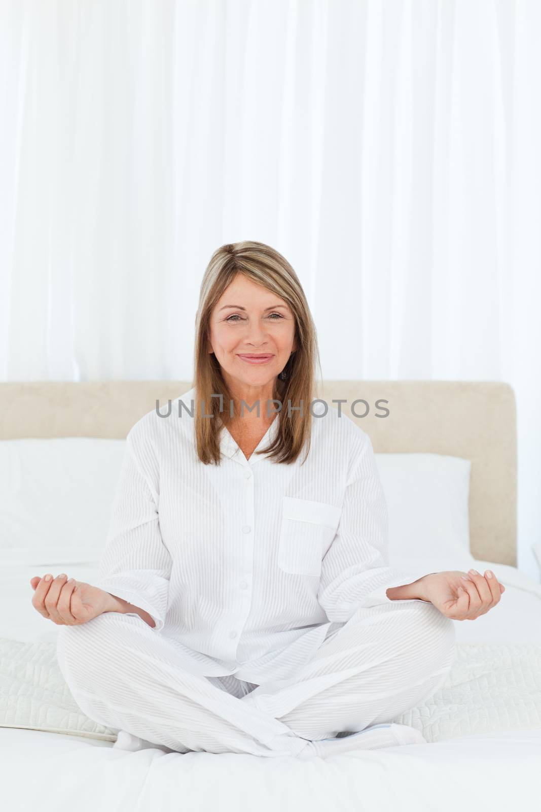 Senior practicing yoga on her bed at home