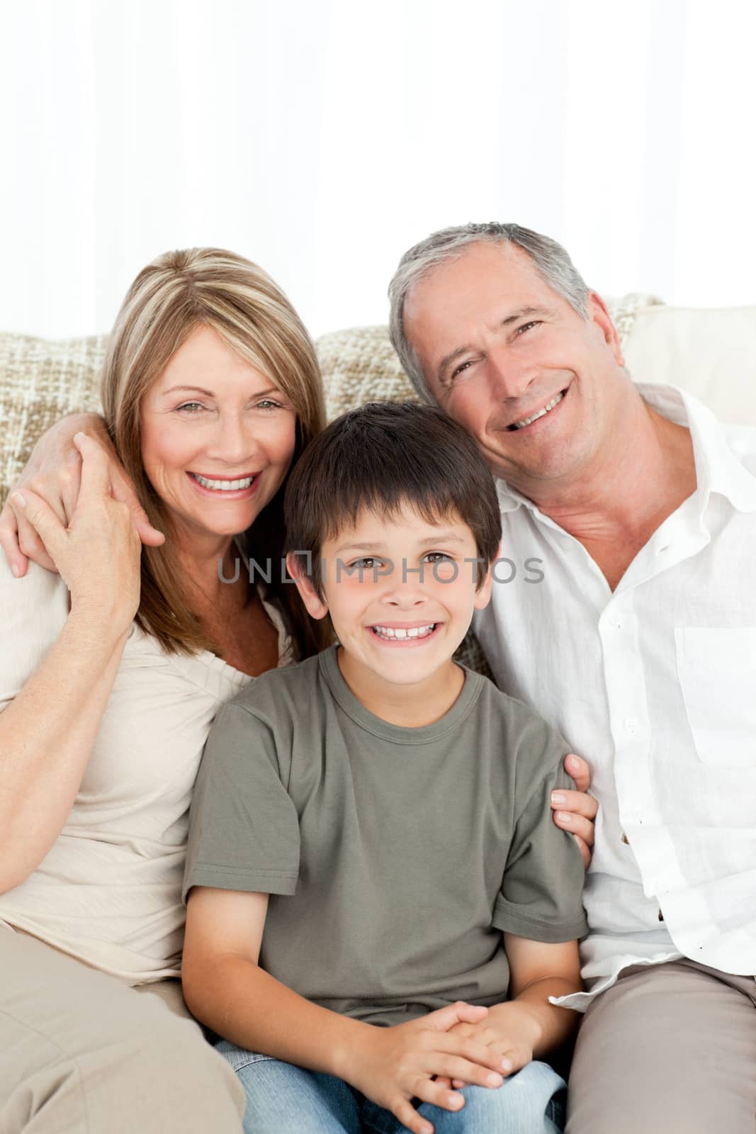 A little boy with his grandparents looking at the camera at home